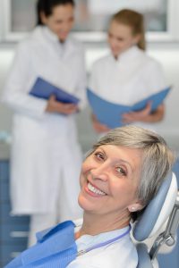 Senior woman patient with dentist team at dental surgery smiling